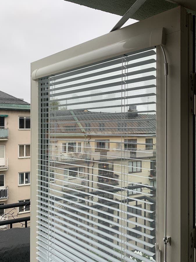 Frihängande designpersienn i ett fönster mot trädgården